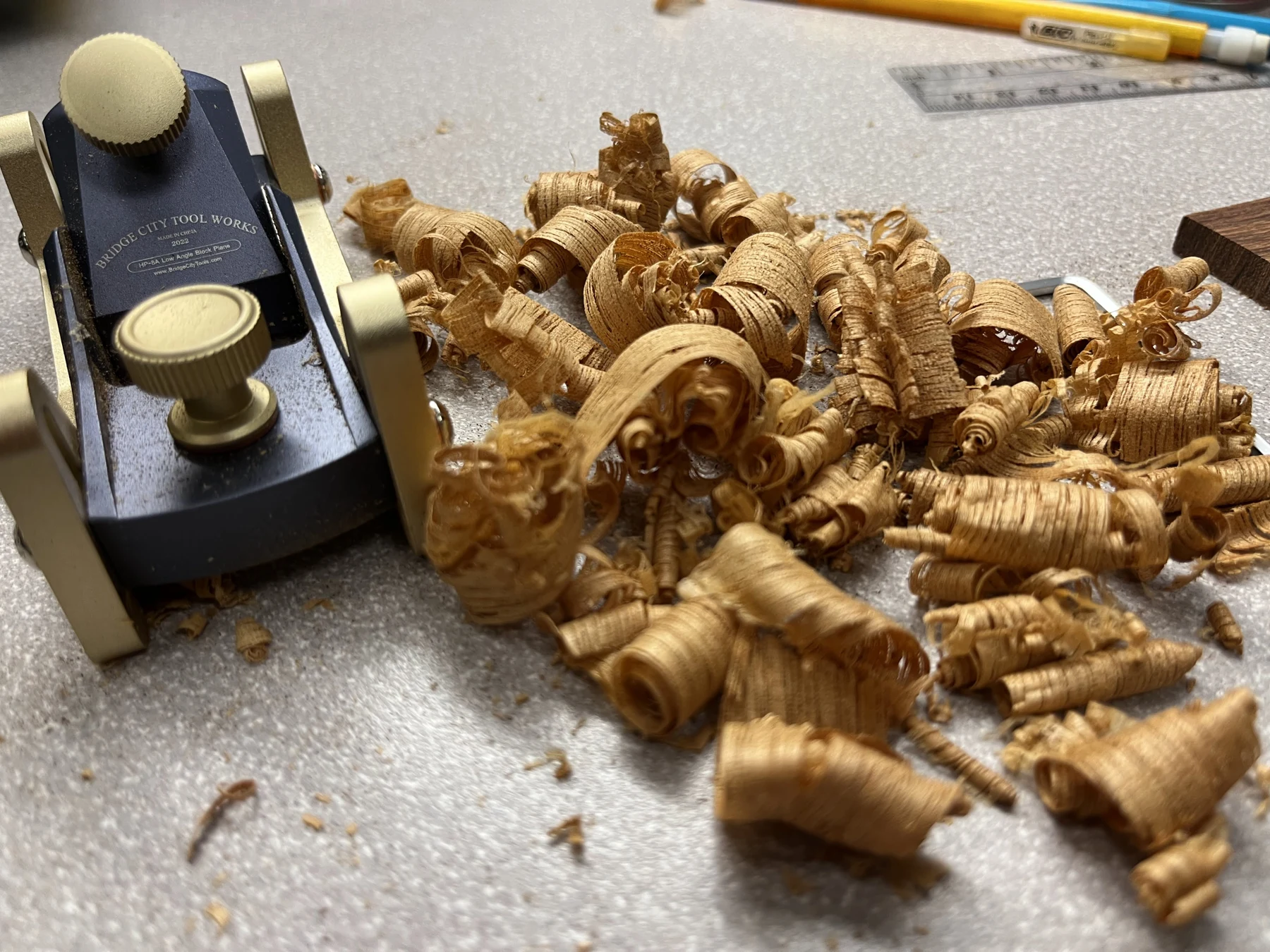 A hand plane beside curled wood shavings on the workbench